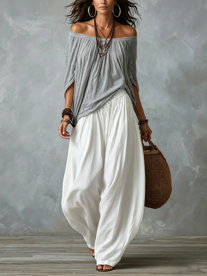 Blusa gris de hombros al aire y pantalones blancos de pierna acampanada