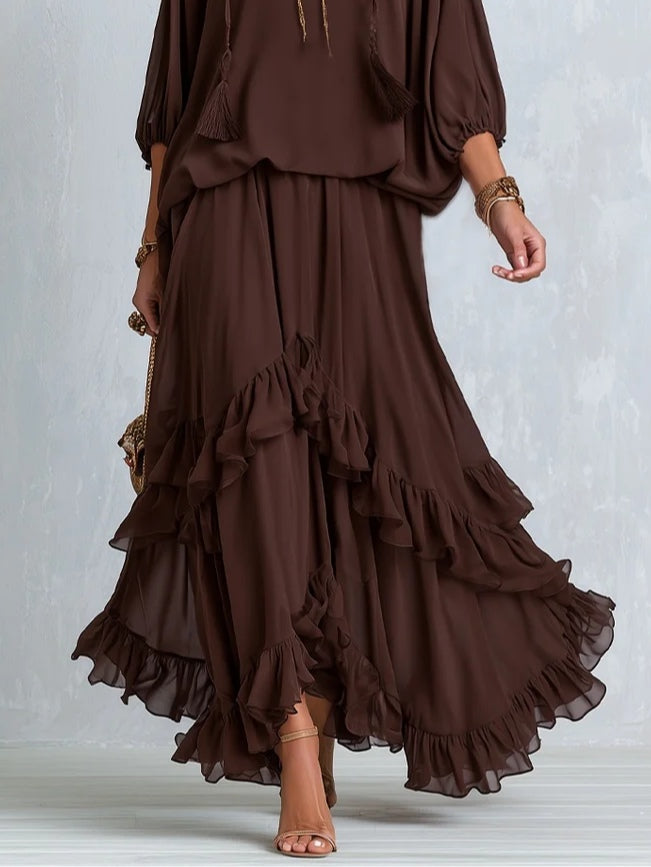 Blusa de gasa marrón con escote en V y flecos, acompañada de un conjunto de falda de capas con volantes